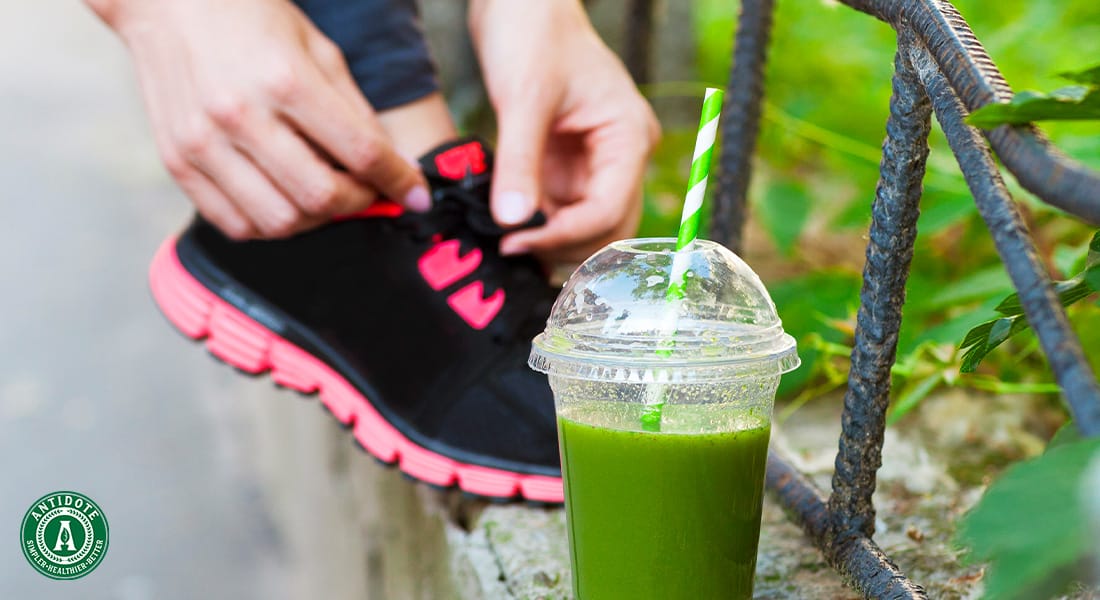 runner tying their shoes beside a green smoothie