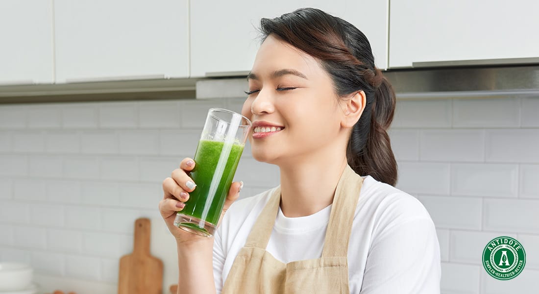 woman wearing apron drinking green smoothie