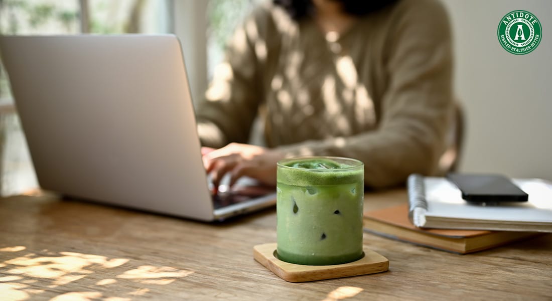 Green juice beside a person working on a laptop.