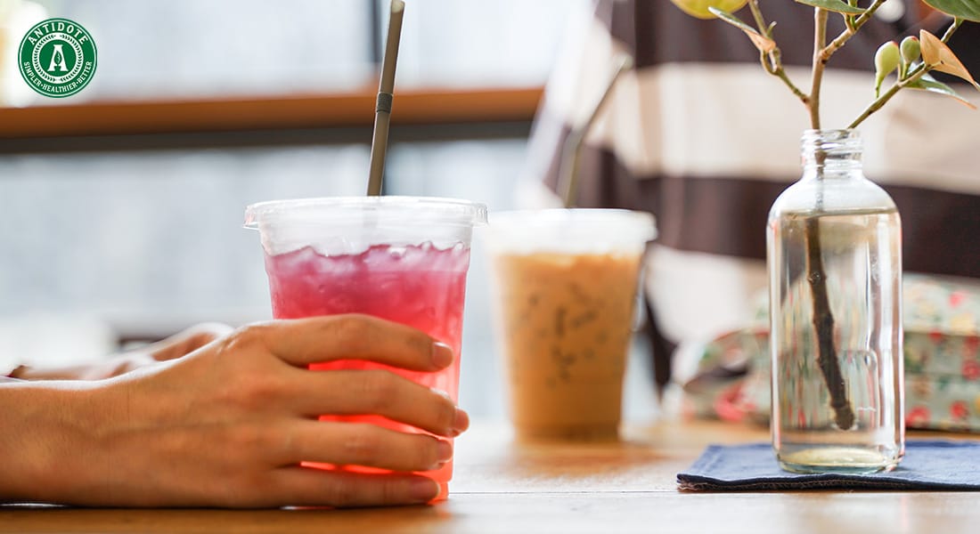 Hand holding a vibrant pink drink at a cafe table.