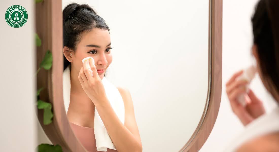 Woman cleaning face, linking skin health to gut health.