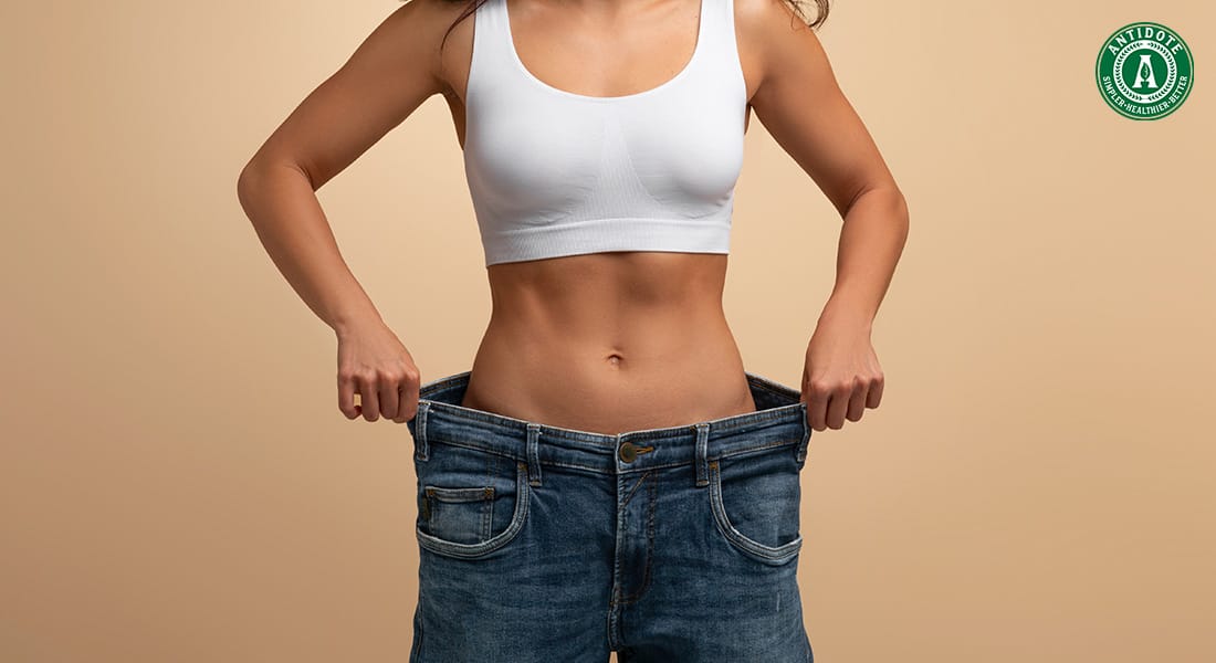 Woman showing weight loss from healthy habits.